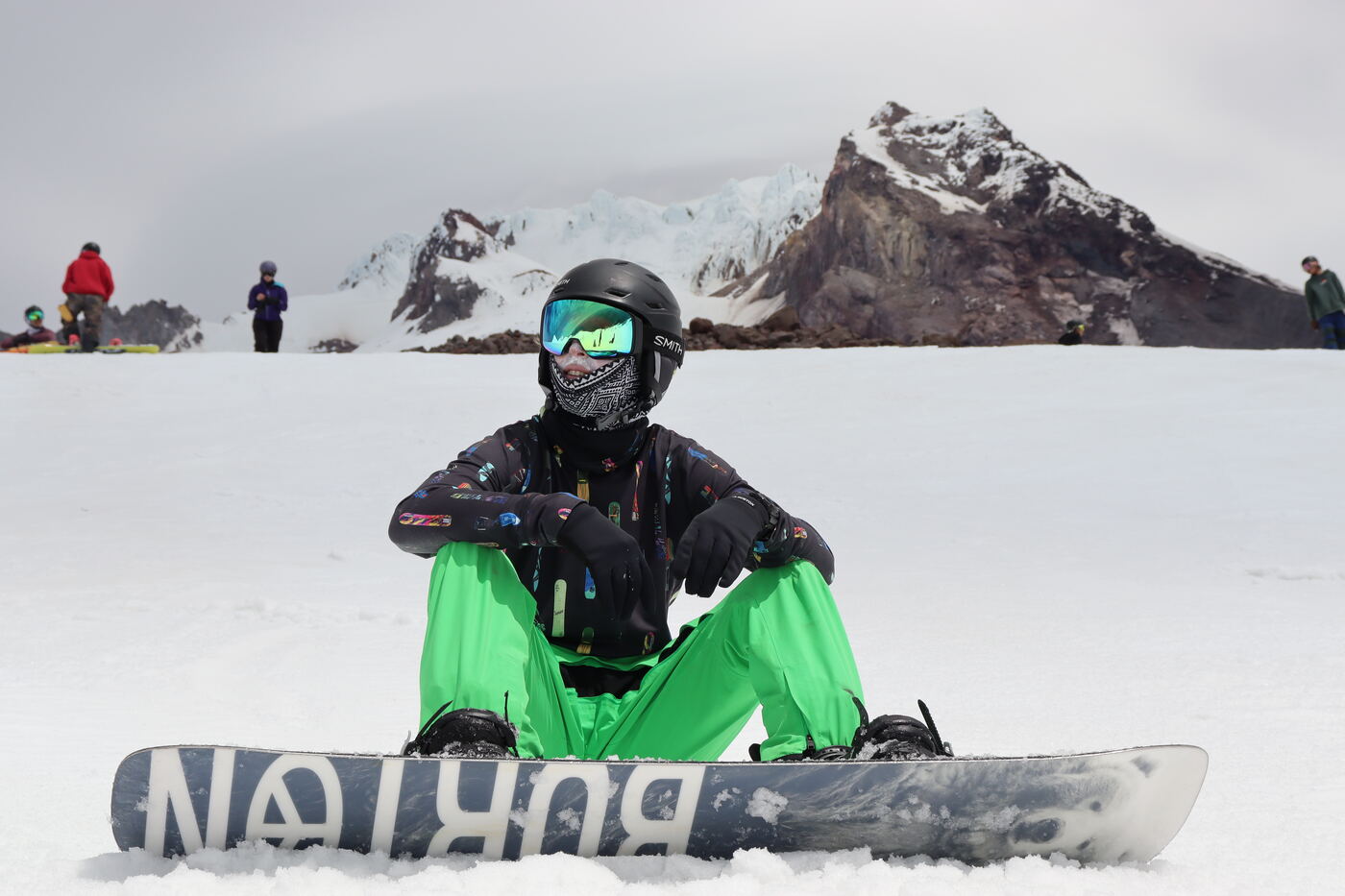 A rider sitting on the snow strapping in